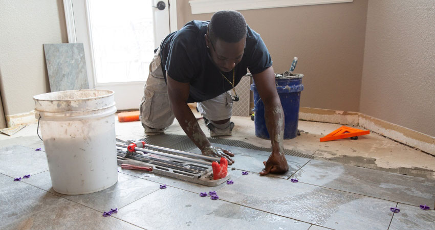 African American male laying ceramic tile