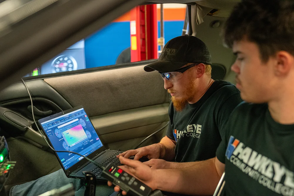 Students sitting in the Camaro working on a laptop.