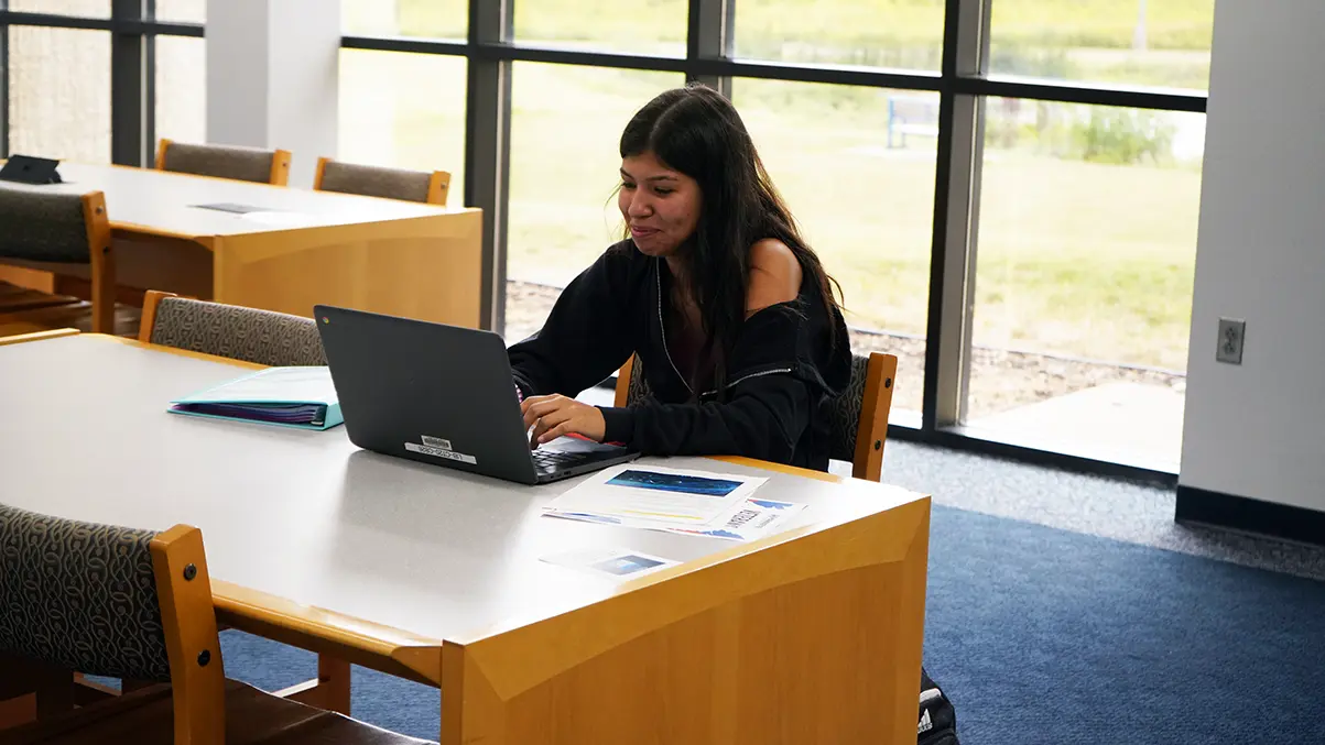 Student participates in an online class discussion in the library.