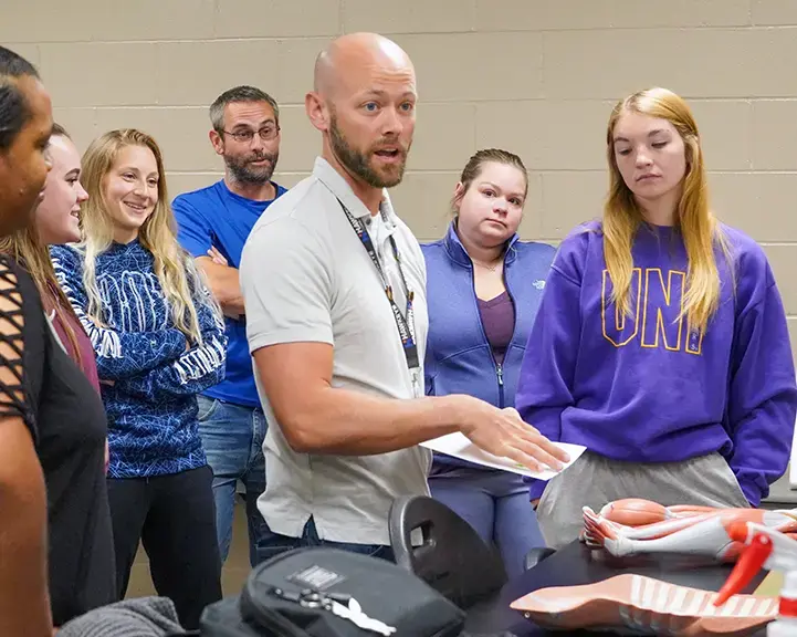 Students in a kinesiology class listen as their instructor shares information about how a body responds to exercise.  