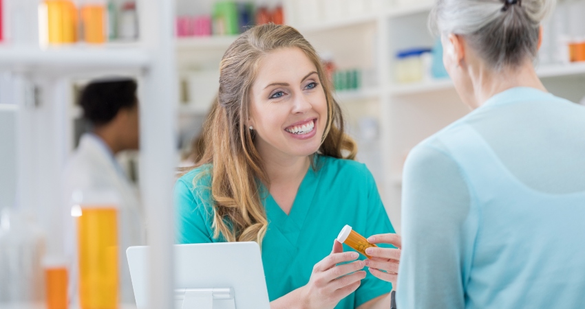 person in a pharmacy handing prescription to a patient